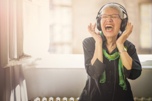 A happy senior woman listening to music on her headphones, one of the many music activities for seniors