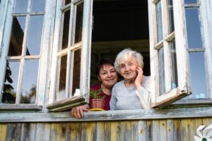 A daughter and mother looking out of an apartment window, highlighting the idea of aging at home
