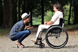 A young woman crouching in front of a wheelchair, highlighting the idea of unconventional caregivers